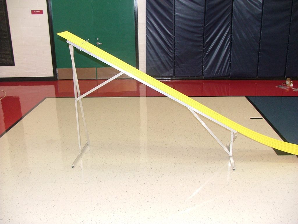 A Derby Magic pinewood derby track set up for a race in a gymnasium