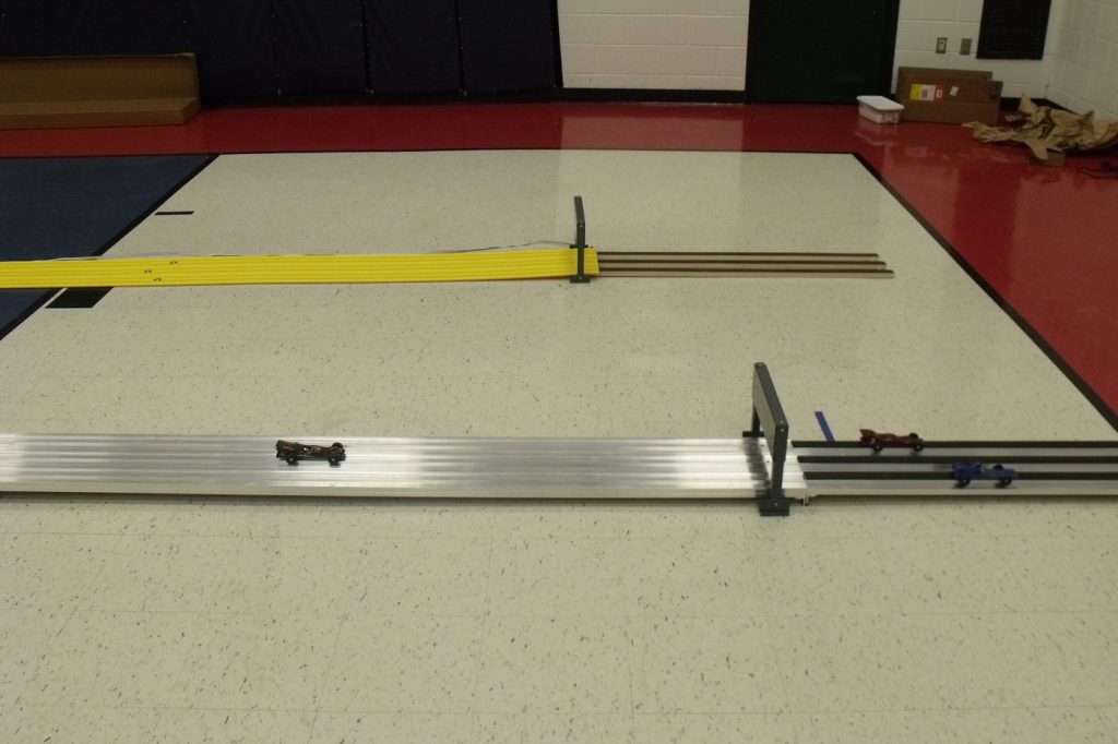 A full Derby Magic pinewood derby track set up in a gymnasium for a community event